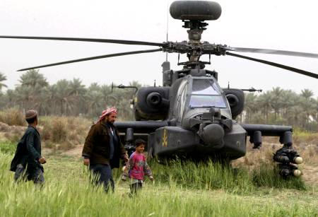Iraqis passing an Apache military helicopter, Hindiya district, 120 km south-west of Baghdad, March 24, 2003.